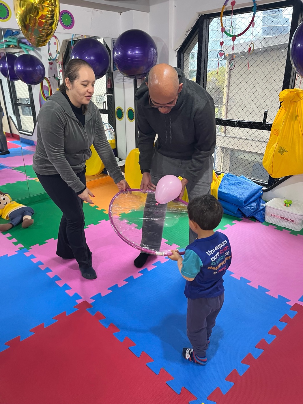 Pedagoga e acompanhante conduzindo uma atividade lúdica com o bebê durante a aula na Baby Gym Itaim Bibi