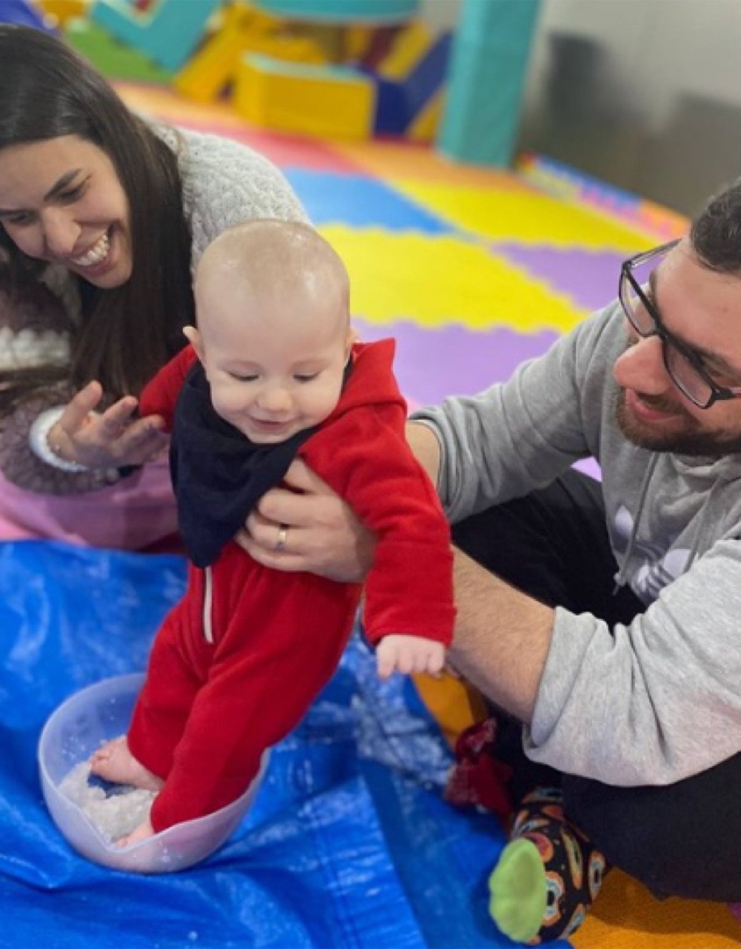 Mãe, pai e bebê sorrindo juntos durante uma aula na Baby Gym Itaim Bibi